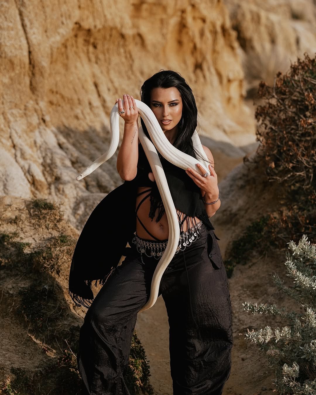 Editorial portrait with a white snake against ochre cliffs